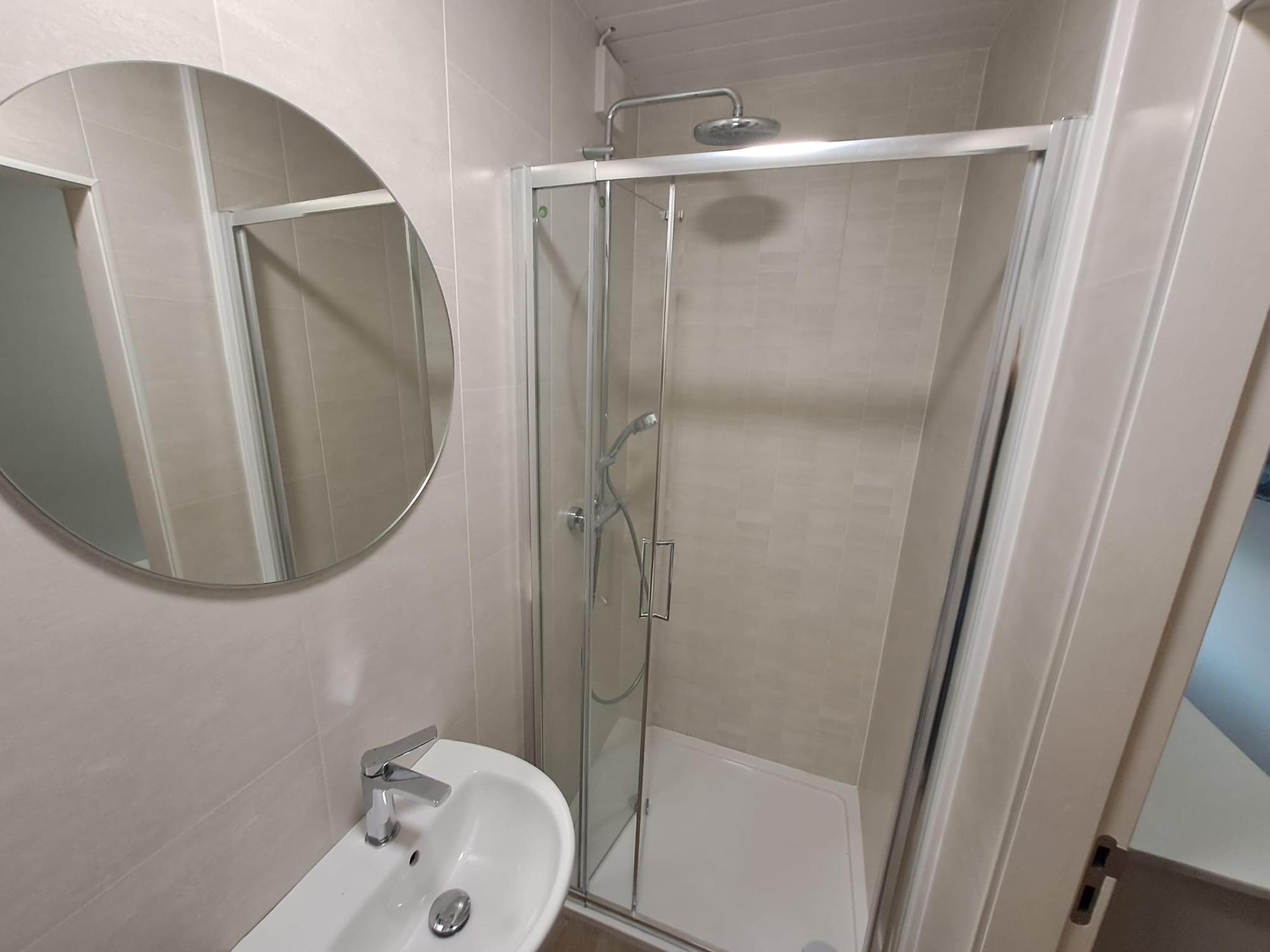 Bathroom with shower, round mirror and towel rail