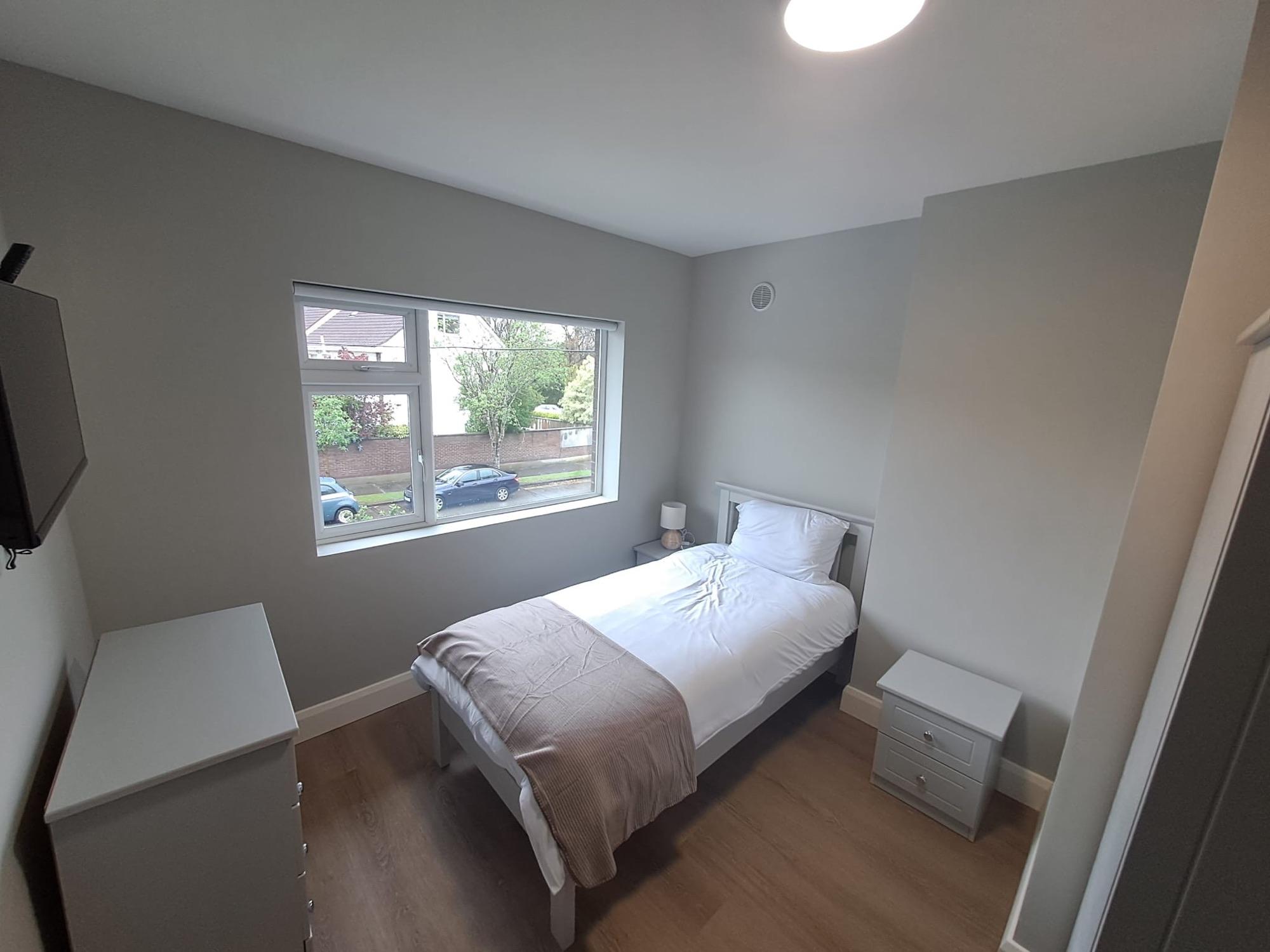 A young person's room with a made-up bed and bright window