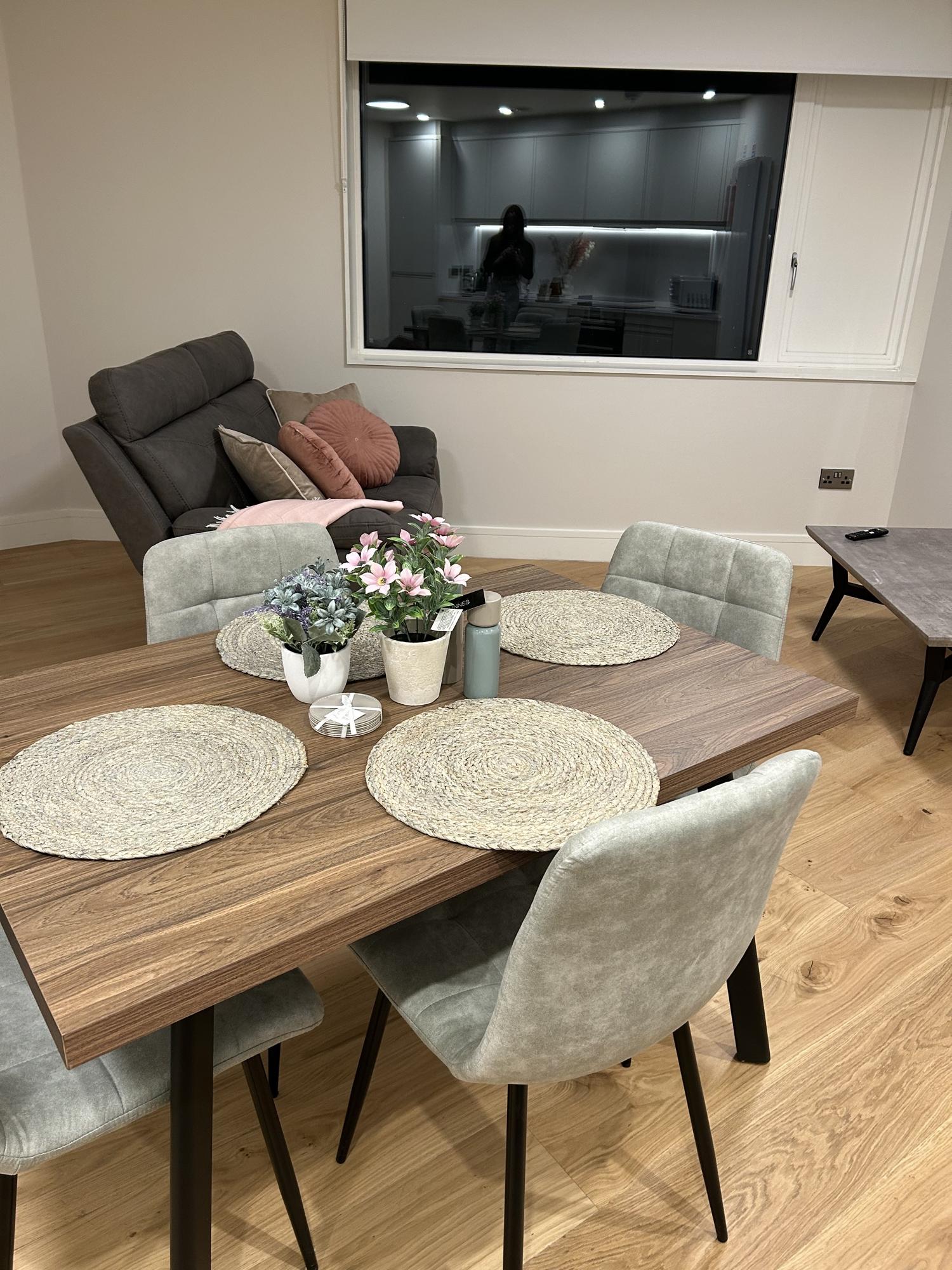 Dining table set for a shared meal, with the living area beyond
