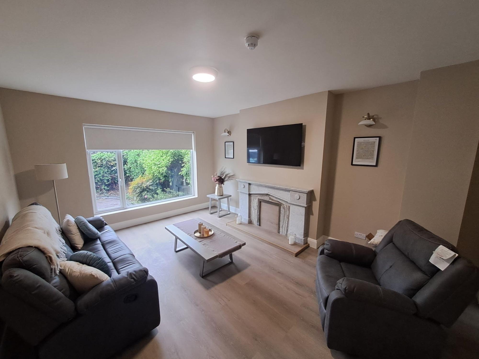 Living room with two grey sofas, a fireplace and a wall-mounted TV