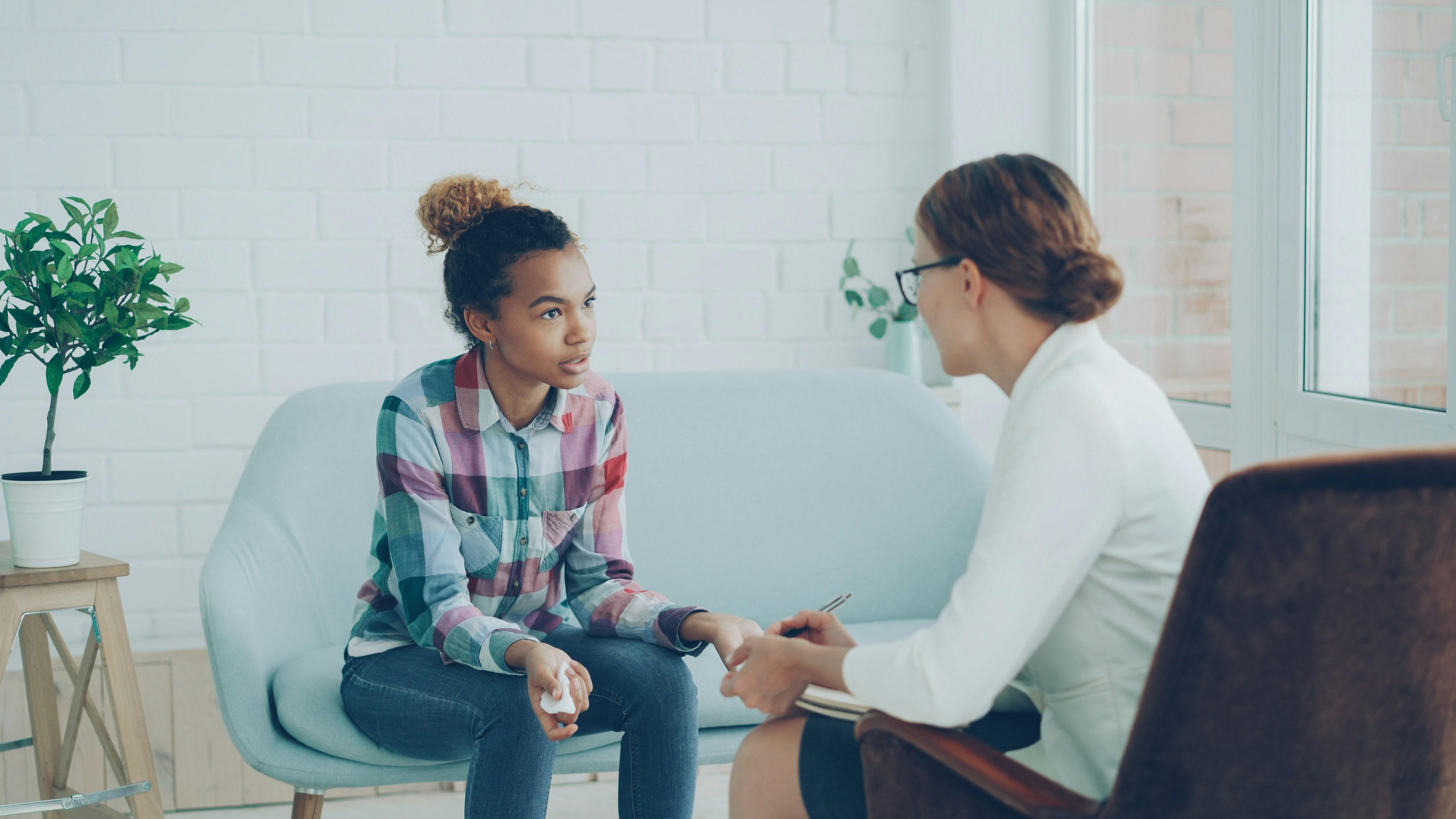 A team member sitting with a young person on a sofa, fully present in conversation.